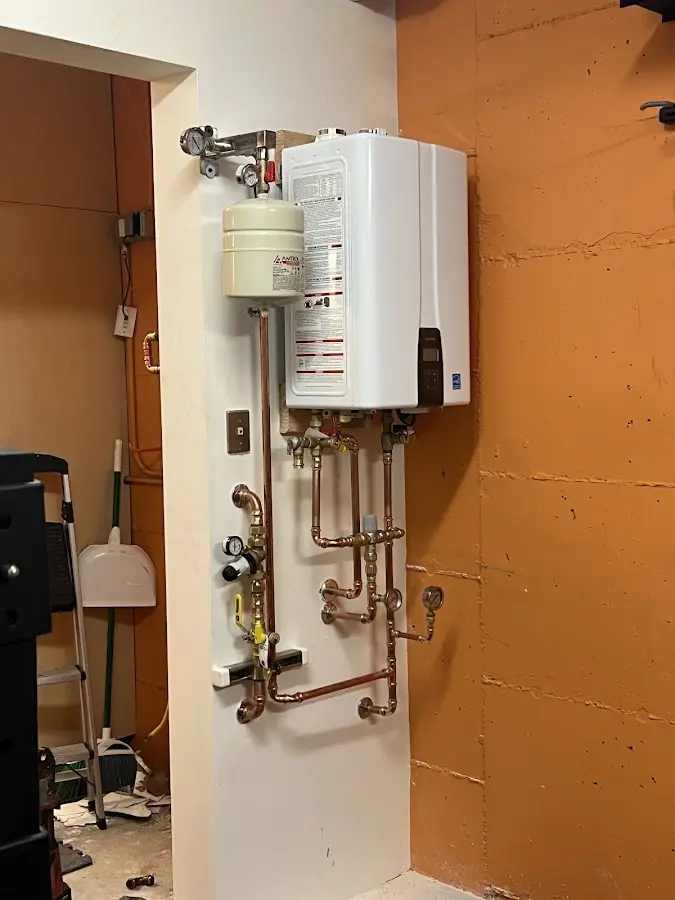 Plumbing technician inspecting water heater connections in West Burlington
